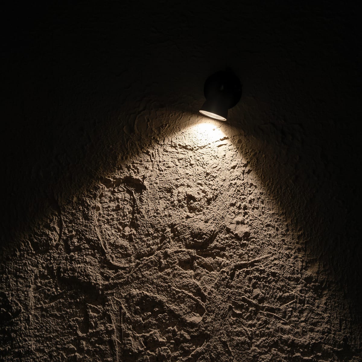 Wall light raking across a textured 3D wall to reveal the relief